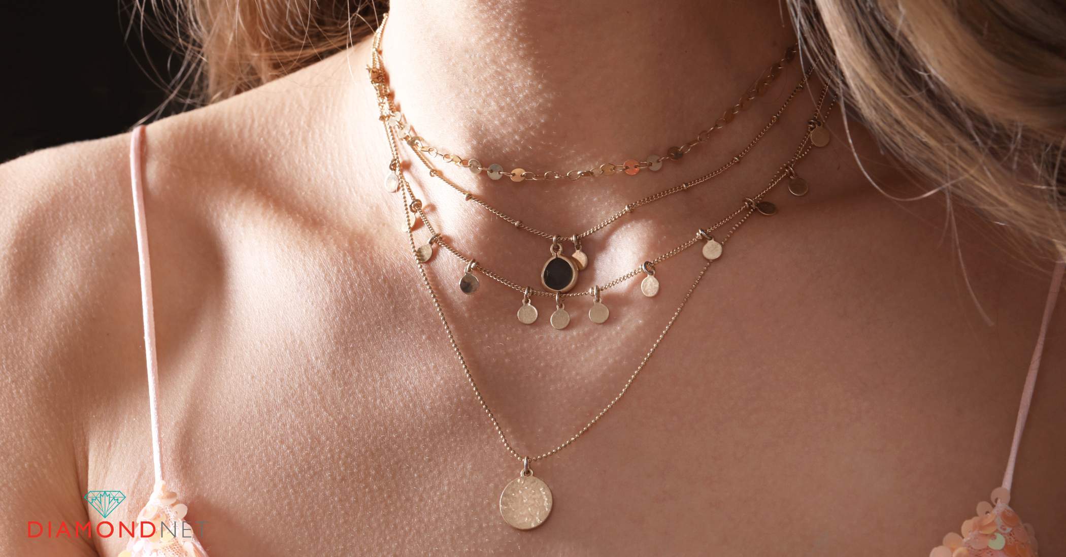 A gold necklace layered with silver necklaces