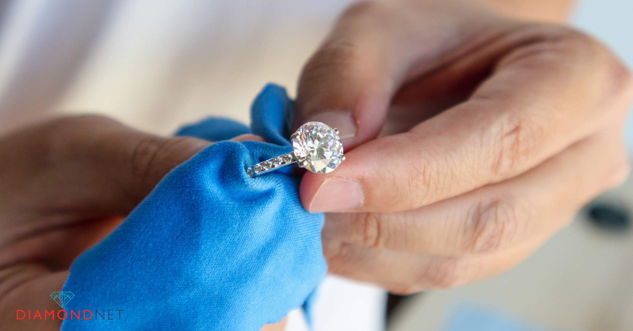 A person holding a toothbrush and a diamond ring, symbolizing care for white gold jewellery maintenance.