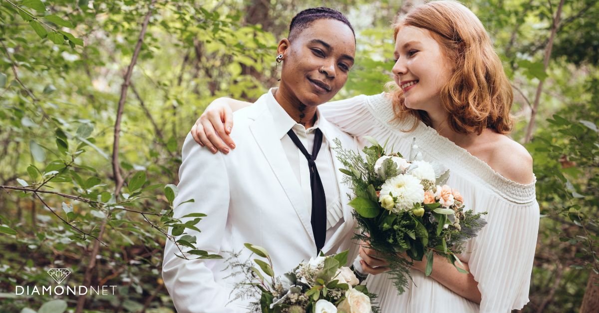 Two brides in beautiful wedding dresses pose in front of a vibrant green arch, showcasing LGBTQIA+ wedding inspiration