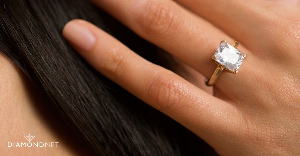 A woman showcases a gold ring adorned with emeralds, highlighting minimalist design in metals and stones
