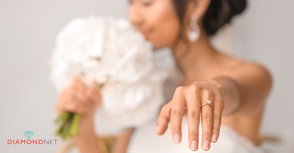 A woman's hand elegantly holds a minimalist engagement ring featuring a sparkling diamond