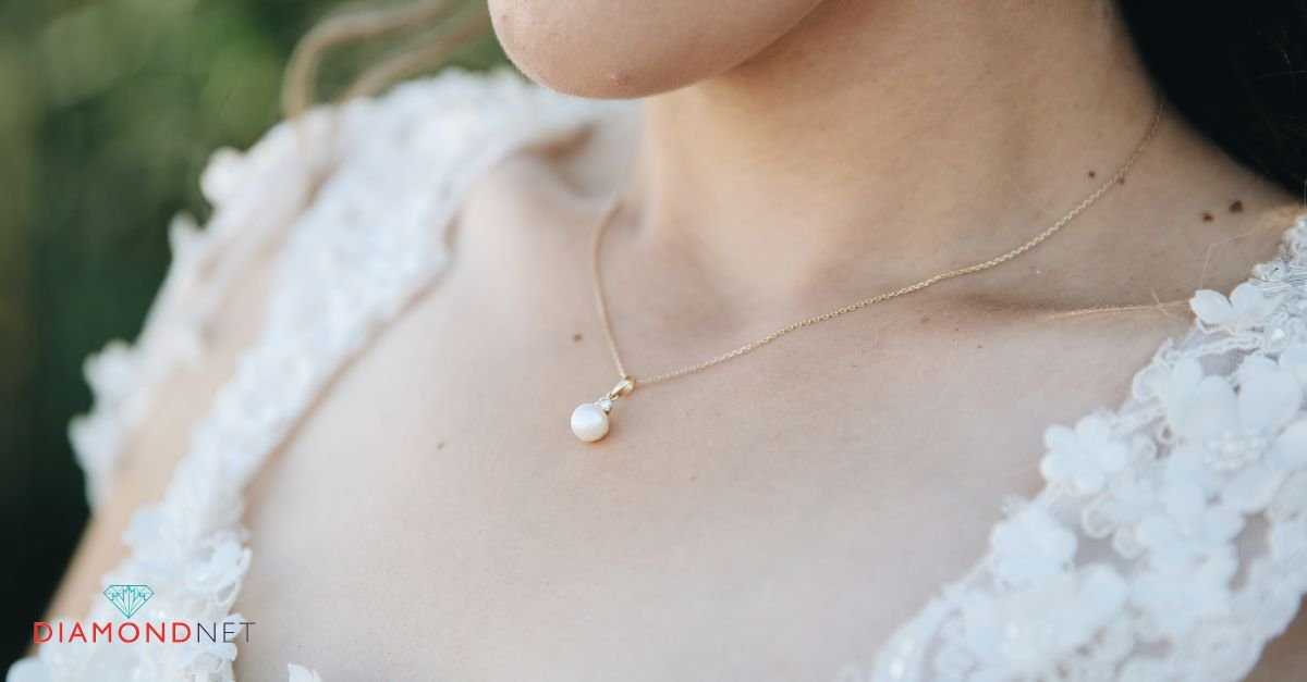 A woman wearing a wedding dress fastens her necklace, thoughtfully matching her bridal jewelry to her gown