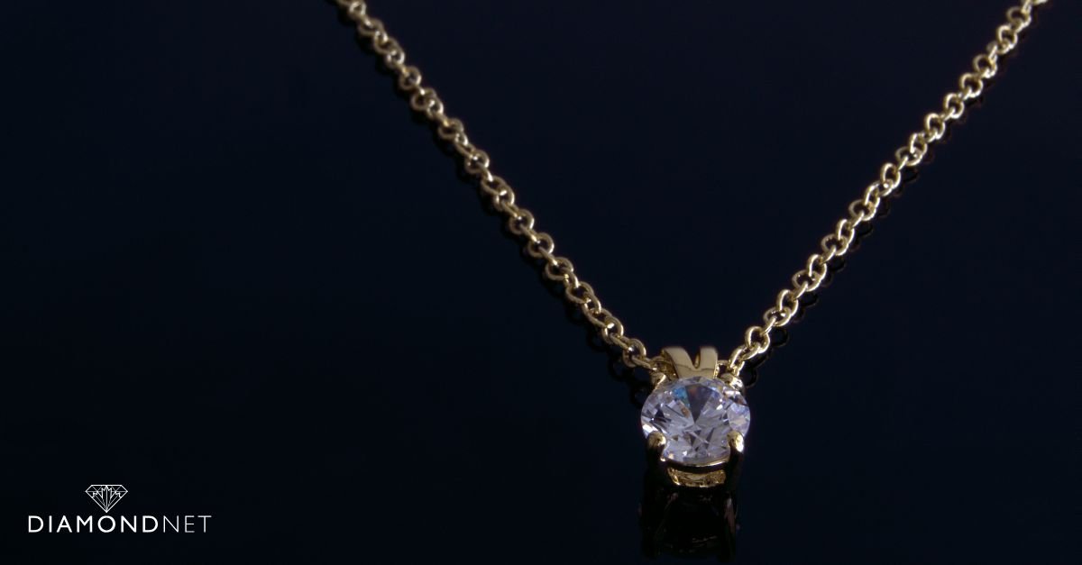 A single-diamond solitaire necklace on a white silk backdrop
